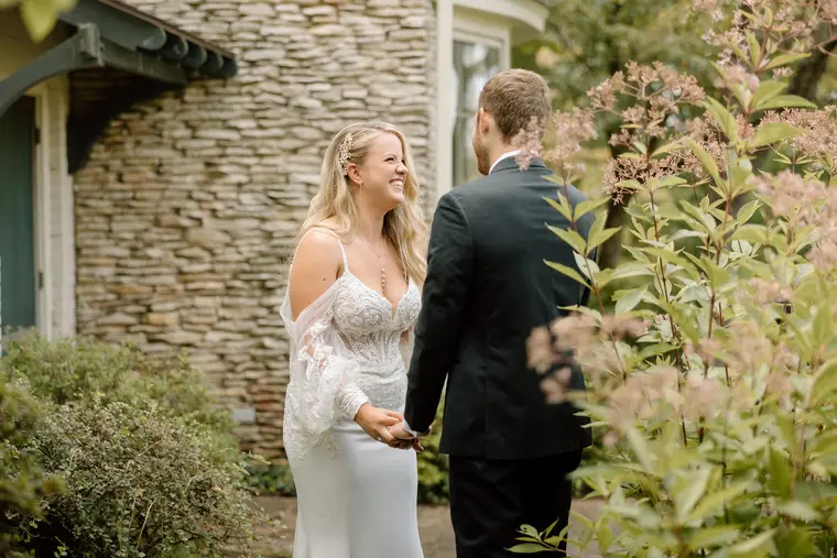 The bride laughing against the stone wall