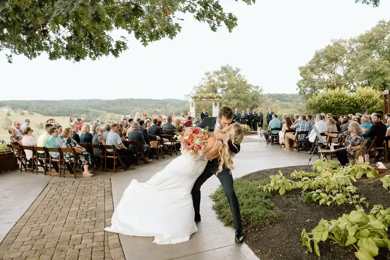The groom dips the bride for a kiss in the aisle