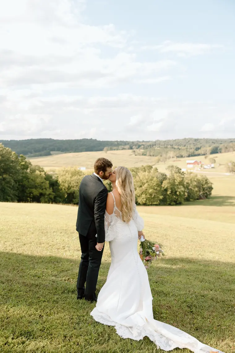 The couple kissing on the open hilltop