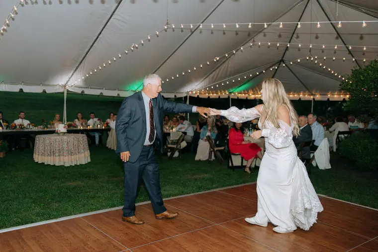 The father and daughter dance under the string lights