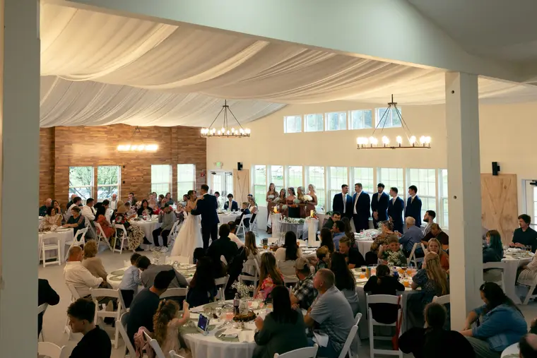 The barn set for dinner with guests at round tables
